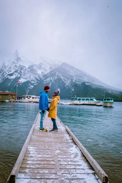 Lake Minnewanka Banff parque nacional Canadá, casal andando junto ao lago durante tempestade de neve em outubro nas Montanhas Rochosas canadenses Canadá — Fotografia de Stock