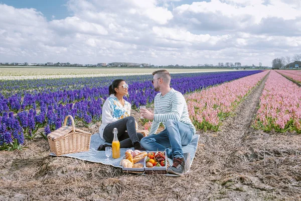 Spring flower season in the Netherlands, couple having a picnic during sprin in the bulb region by Lisse with Hyacinth flowers field on the background — Stock Photo, Image
