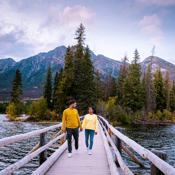 couple by the lake watching sunset, Pyramid lake Jasper during autumn in Alberta Canada, fall colors by the lake during sunset, Pyramid Island Jasper