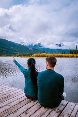 Çiftler göl kenarında gün batımını izliyor, Alberta Kanada 'da sonbahar boyunca Jasper Piramidi, günbatımında göl kenarına düşen renkler, Jasper Piramidi.