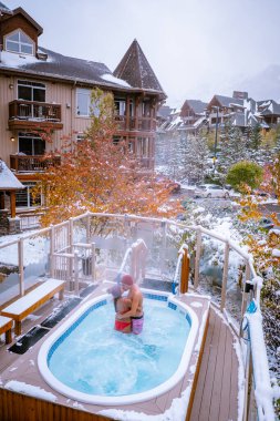 couple in hot tub during snow in the Canadian rockies in Canada, men and woman in hot tub