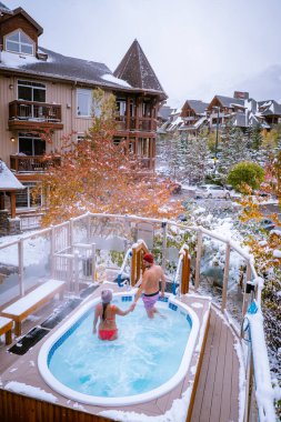couple in hot tub during snow in the Canadian rockies in Canada, men and woman in hot tub