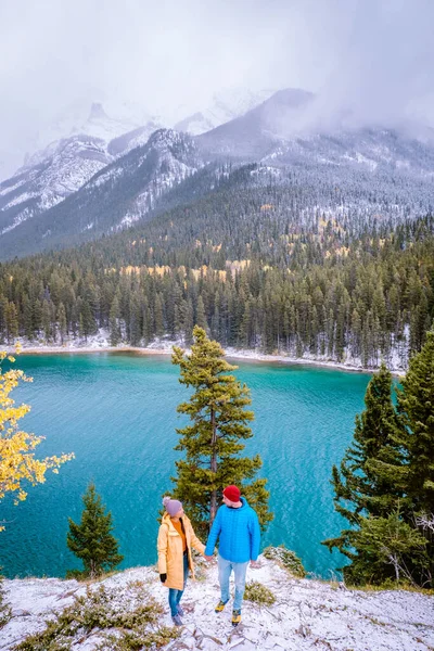 Lake Minnewanka Banff parque nacional Canadá, casal andando junto ao lago durante tempestade de neve em outubro nas Montanhas Rochosas canadenses Canadá — Fotografia de Stock