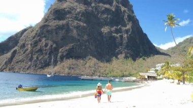 Saint Lucia şeker plajı St Lucia dağlarında dev piton drone manzarası, tatil sırasında beyaz şeker plajında debelenen birkaç erkek ve kadın.