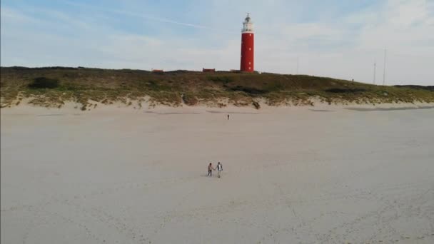 Günbatımında Texel deniz feneri Hollanda Hollanda adası Tekel 'i, Ebach' ta yürüyen çift — Stok video