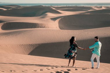 Maspalomas sahilinde yürüyen çift Gran Canaria İspanya, Maspalomas 'ın kum tepeleri çölünde kadın ve erkek.