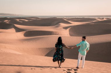 Maspalomas sahilinde yürüyen çift Gran Canaria İspanya, Maspalomas 'ın kum tepeleri çölünde kadın ve erkek.