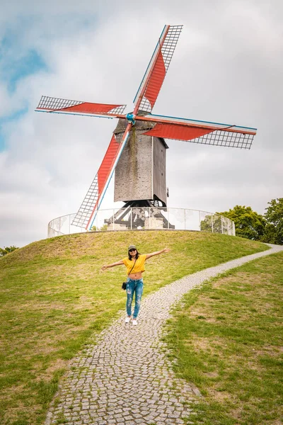 Brujas Bélgica, colorida casa en la ciudad vieja de Brujas, joven mujer libre en la ciudad por el viejo molino de viento, Brujas, Bélgica. Molino de viento de San Janshuismolen que data de 1770, todavía en su lugar original —  Fotos de Stock