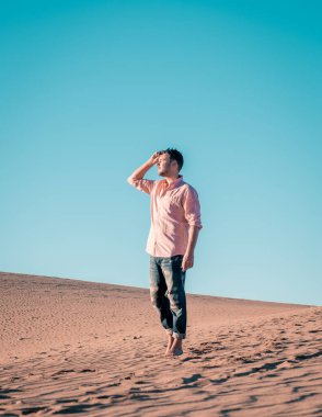 Maspalomas sahilinde yürüyen bir adam Gran Canaria İspanya 'da, Maspaloma' nın kum tepelerinde yürüyen bir adam.