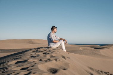 Maspalomas sahilinde yürüyen bir adam Gran Canaria İspanya 'da, Maspaloma' nın kum tepelerinde yürüyen bir adam.