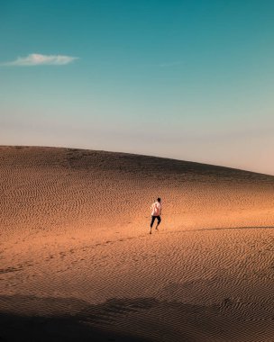 Maspalomas sahilinde yürüyen bir adam Gran Canaria İspanya 'da, Maspaloma' nın kum tepelerinde yürüyen bir adam.