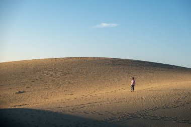 Maspalomas sahilinde yürüyen bir adam Gran Canaria İspanya 'da, Maspaloma' nın kum tepelerinde yürüyen bir adam.