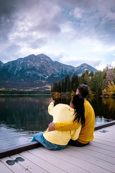 Пара у озера наблюдая закат, Пирамида озера Джаспер в течение осени в Альберте Канада, падать цвета на озере во время заката, Пирамида острова Джаспер — стоковое фото