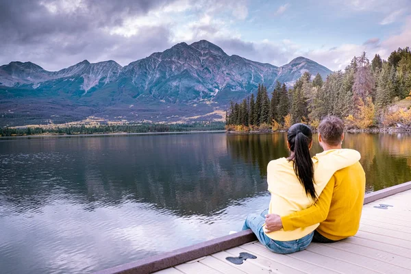 Pareja por el lago viendo la puesta del sol, Pirámide lago Jasper durante el otoño en Alberta Canadá, caída de colores por el lago durante la puesta del sol, Pirámide isla Jasper —  Fotos de Stock