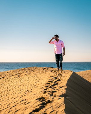 Maspalomas sahilinde yürüyen bir adam Gran Canaria İspanya 'da, Maspaloma' nın kum tepelerinde yürüyen bir adam.