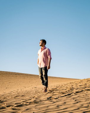Maspalomas sahilinde yürüyen bir adam Gran Canaria İspanya 'da, Maspaloma' nın kum tepelerinde yürüyen bir adam.