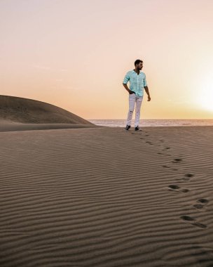 Maspalomas sahilinde yürüyen bir adam Gran Canaria İspanya 'da, Maspaloma' nın kum tepelerinde yürüyen bir adam.