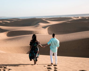 Maspalomas sahilinde yürüyen çift Gran Canaria İspanya, Maspalomas 'ın kum tepeleri çölünde kadın ve erkek.