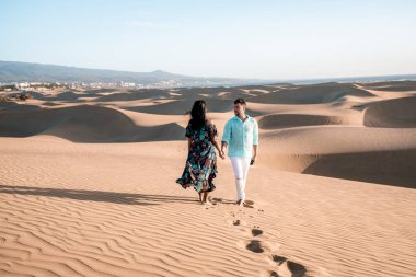 Maspalomas sahilinde yürüyen çift Gran Canaria İspanya, Maspalomas 'ın kum tepeleri çölünde kadın ve erkek.