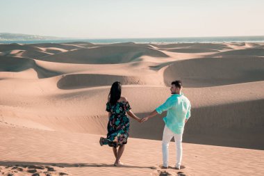 Maspalomas sahilinde yürüyen çift Gran Canaria İspanya, Maspalomas 'ın kum tepeleri çölünde kadın ve erkek.