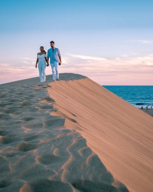 Maspalomas sahilinde yürüyen çift Gran Canaria İspanya, Maspalomas 'ın kum tepeleri çölünde kadın ve erkek.