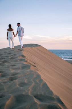 Maspalomas sahilinde yürüyen çift Gran Canaria İspanya, Maspalomas 'ın kum tepeleri çölünde kadın ve erkek.