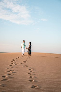 Maspalomas sahilinde yürüyen çift Gran Canaria İspanya, Maspalomas 'ın kum tepeleri çölünde kadın ve erkek.