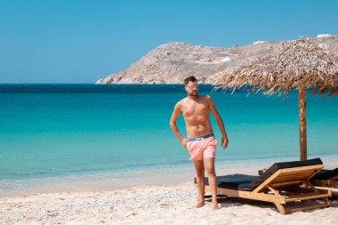 Yunanistan 'da tatil yapan gençler, Yunanistan' da Mikonos, Yunanistan 'da Küçük Venedik Mikonoları, Mykonos şehrinde okyanusta gün batımı