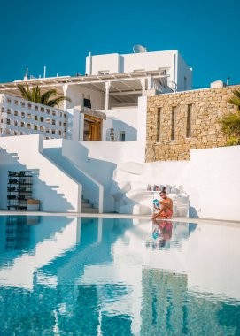 Tatilde olan genç erkekler Mykonos Yunanistan, Mykonos 'ta havuz başında kitap okuyan genç adam.