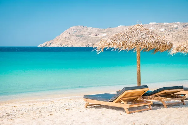 Mykonos Strand im Sommer mit Sonnenschirm und luxuriösen Liegestühlen, blaues Meer mit Berg am Elia Strand Mikonos Griechenland — Stockfoto