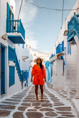 Mykonos Yunanistan 'da tatil yapan kadın, Küçük Venedik Mikonos Yunanistan, Mykonos kasabasında okyanus kenarında gün batımı