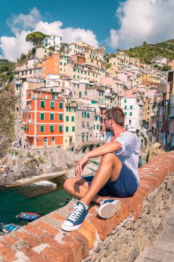 La Spezia, İtalya 'daki Cinque Terre' den Riomaggiore manzarası. Okyanus ötesine bakan mutlu genç çift dağda piknik yapıyor.