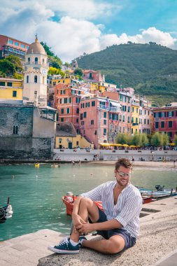La Spezia, İtalya 'daki Cinque Terre' den Vernazza 'nın manzarası. Okyanus ötesine bakan mutlu genç çift dağda piknik yapıyor.