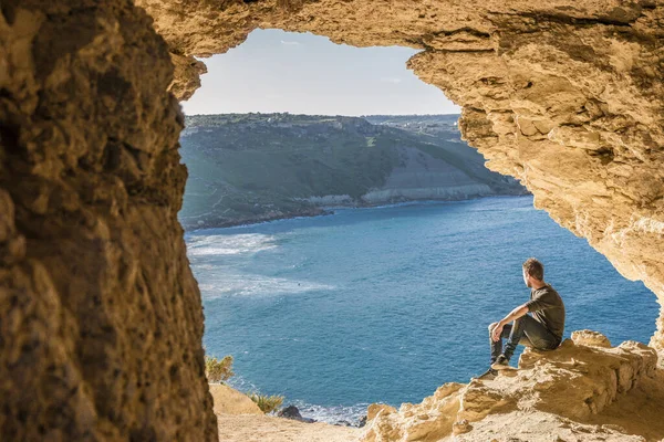 Gozo Adası Malta, bir mağarada genç adam okyanusa bakıyor ve Tal Mixta Mağarası Gozo 'nun içinden Ramla Körfezi manzarası. 