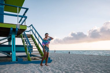 Miami plajı, Florida sahilindeki cankurtaran kulübesinde bir kadın, plajda bikinili bir kız.