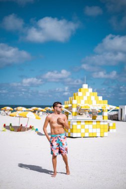 Miami plajı Florida, renkli cankurtaran kulübesi olan genç erkekler, tatil sırasında Miami 'de sahilde yürüyen bir adam.