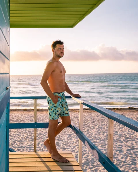 Miami plajı Florida, renkli cankurtaran kulübesi olan genç erkekler, tatil sırasında Miami 'de sahilde yürüyen bir adam. — Stok fotoğraf