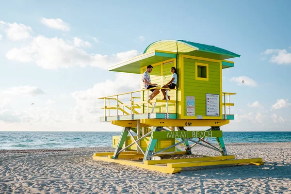 Miami South Beach Florida, pár életmentő kunyhó alatt Sunrise Miami Beach, férfiak és nők a strandon — Stock Fotó