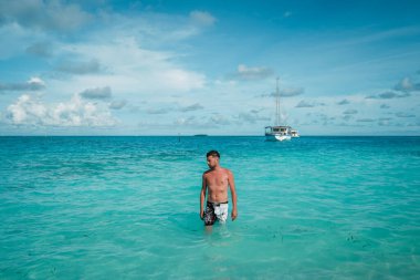 Maldivler, Maldivler adasının sahillerinde kısa yüzen genç adam, kristal berrak beyaz kumsalda ve okyanusta
