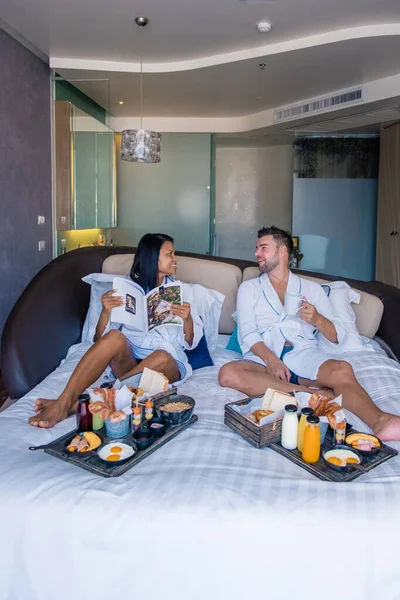 Breakfast in bed of an luxury hotel room, brekafast with eg and juice in bedroom, couple in bed having breakfast