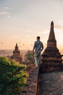 Bagan Myanmar 'lı genç adamlar eski bir tapınağın çatısından Sunrise' ı izliyorlar, adam gün batımını seyrediyor, pagoda tapınağı Bagan Burma