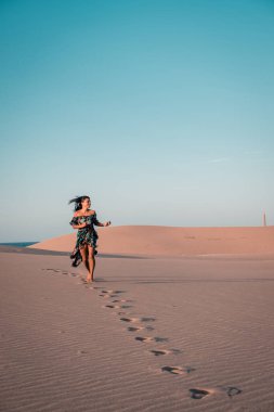 Maspalomas sahilinde yürüyen kadın Gran Canaria İspanya 'da, Maspaloma' nın kum tepelerinde yürüyen kız