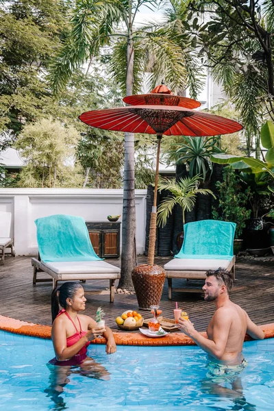 Felice giovane coppia che prende un cocktail a bordo piscina durante le vacanze, pranzo di coppia a bordo piscina, uomini e donne durante le vacanze vacanza di lusso in Myanmar — Foto Stock