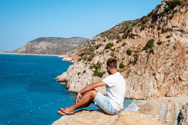 Kaputas Beach Kas pavo, playa de color naranja blanco desde los acantilados junto al océano de Kas Turquía rivera, los hombres de pie en el acantilado mirando el océano — Foto de Stock