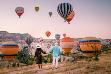 Gündoğumunda Kapadokya Türkiye, Goreme Kapadokya tepelerinde tatil yapan iki orta yaşlı erkek ve kadın, Kapadokya 'da sıcak hava balonlarıyla güneşlenen erkek ve kadın