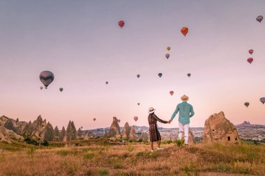 Gündoğumunda Kapadokya Türkiye, Goreme Kapadokya tepelerinde tatil yapan iki orta yaşlı erkek ve kadın, Kapadokya 'da sıcak hava balonlarıyla güneşlenen erkek ve kadın