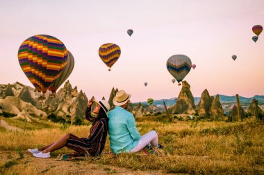 Gündoğumunda Kapadokya Türkiye, Goreme Kapadokya tepelerinde tatil yapan iki orta yaşlı erkek ve kadın, Kapadokya 'da sıcak hava balonlarıyla güneşlenen erkek ve kadın