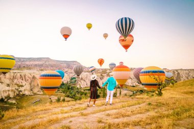 Gündoğumunda Kapadokya Türkiye, Goreme Kapadokya tepelerinde tatil yapan iki orta yaşlı erkek ve kadın, Kapadokya 'da sıcak hava balonlarıyla güneşlenen erkek ve kadın