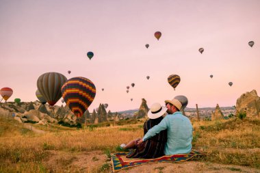 Gündoğumunda Kapadokya Türkiye, Goreme Kapadokya tepelerinde tatil yapan iki orta yaşlı erkek ve kadın, Kapadokya 'da sıcak hava balonlarıyla güneşlenen erkek ve kadın