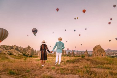 Gündoğumunda Kapadokya Türkiye, Goreme Kapadokya tepelerinde tatil yapan iki orta yaşlı erkek ve kadın, Kapadokya 'da sıcak hava balonlarıyla güneşlenen erkek ve kadın
